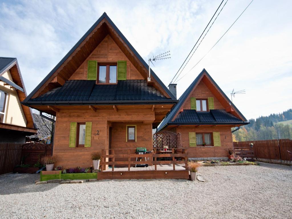 una casa de madera con un banco delante de ella en Apartamenty i Domki Biały Dunajec, en Biały Dunajec