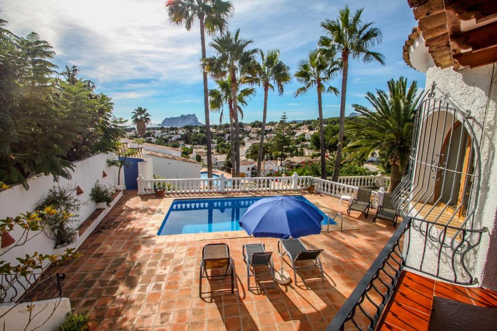 une terrasse avec une piscine, des chaises et un parasol bleu dans l'établissement San Jaime-19M - sea view villa with private pool in Moraira, à Pedramala