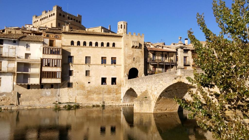 een oud gebouw met een brug over een waterlichaam bij Hotel Querol in Valderrobres