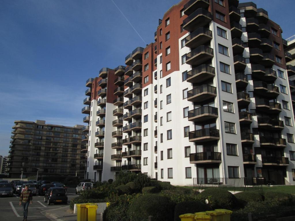a tall apartment building with cars parked in front of it at De Panne Plaza in De Panne