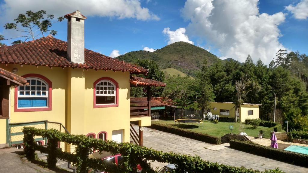 a house with a garden and a mountain in the background at Tarkna - Hotel Holandês in Teresópolis