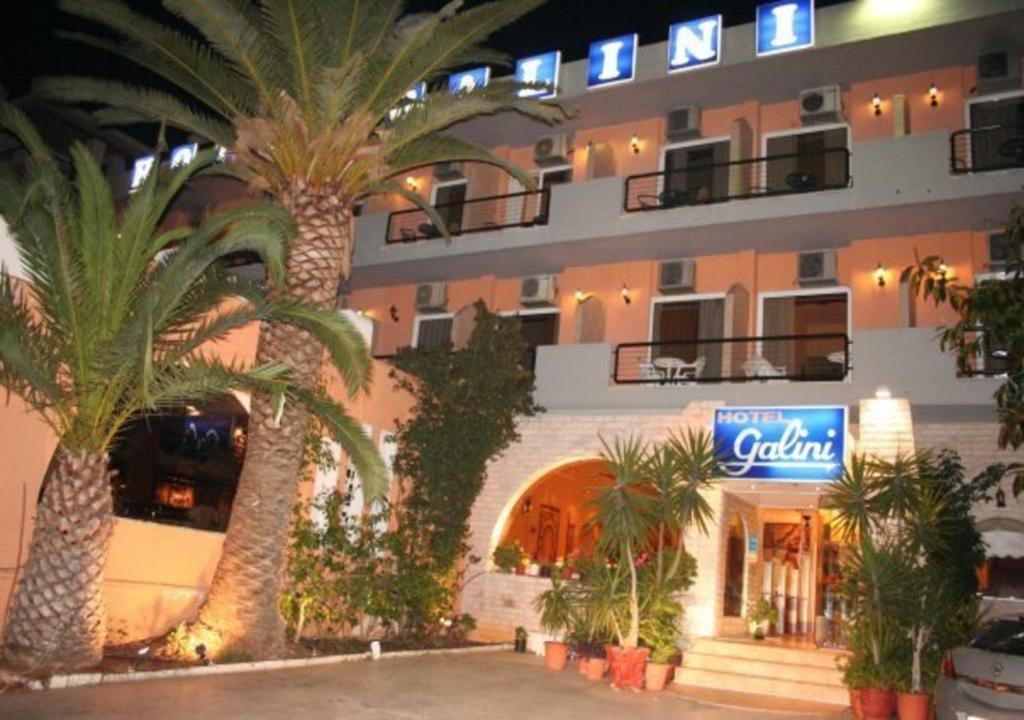 a hotel with palm trees in front of a building at Galini Palace in Athens