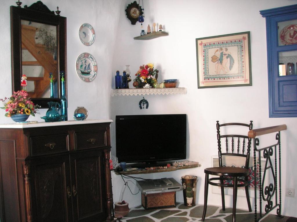 a living room with a tv and a chair at 3-level doll house in Kea Ioulida/Chora, Cyclades in Ioulis