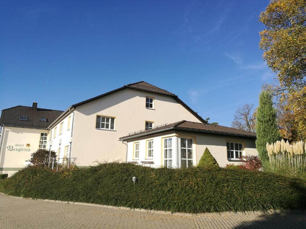 a large white house with a roof at Hotel &amp; Restaurant Bergfried in Saalfeld