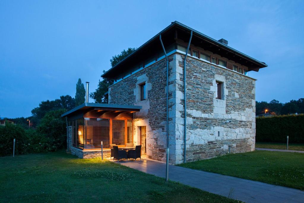 a stone house with a large window on a field at Casa Do Bosque in Sarria
