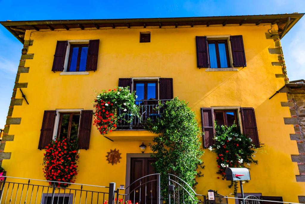 a yellow building with flowering plants and windows at Villa "Corte de' Baldi" in Ortignano Raggiolo