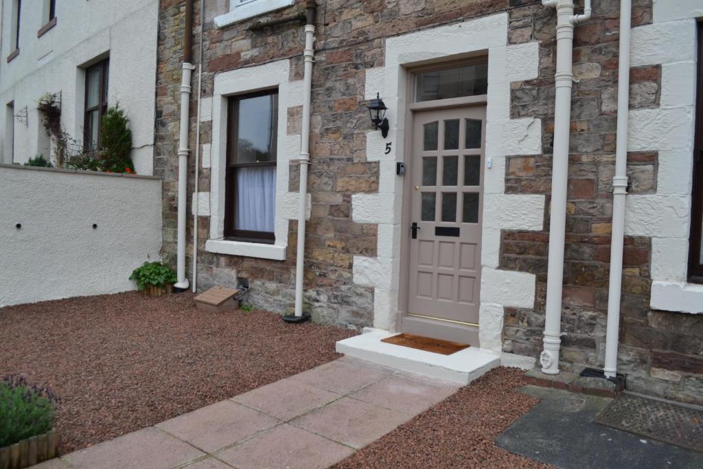 a brick house with a pink door on it at Old Bridge End in Jedburgh