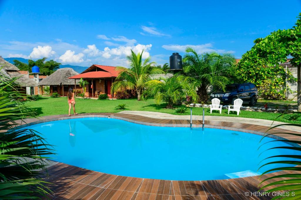 a woman standing in front of a swimming pool in front of a house at Bungalows El Palmiche in Satipo