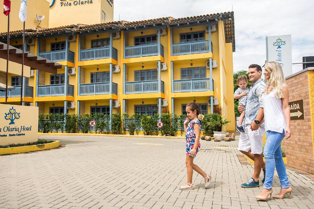 una familia parada frente a un hotel en Vila Olaria Hotel, en Penha