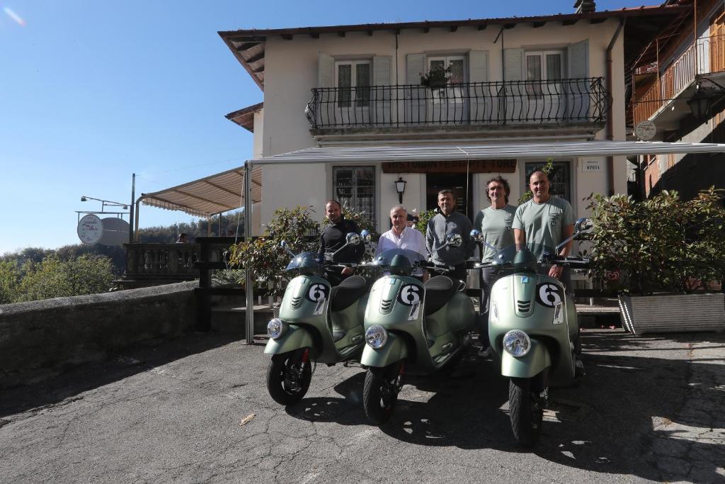 a group of people sitting on scooters in front of a house at Locanda del Pittore in Arcumeggia