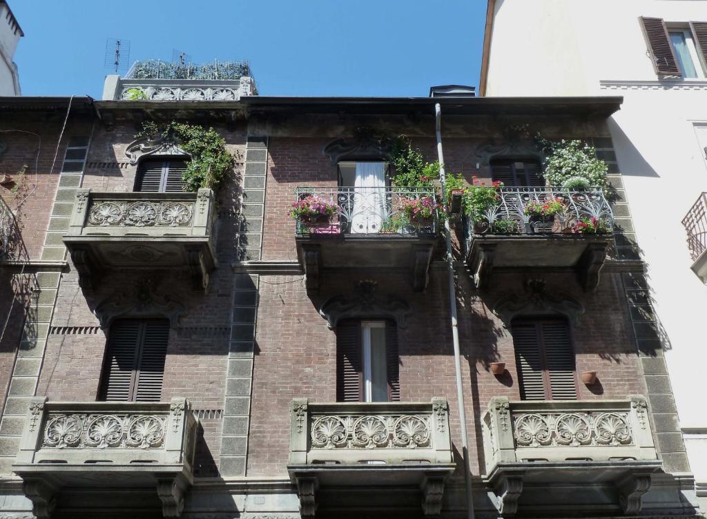 トリノにあるRabadan Bed and Breakfastのレンガ造りの建物で、バルコニーと花箱が備わります。