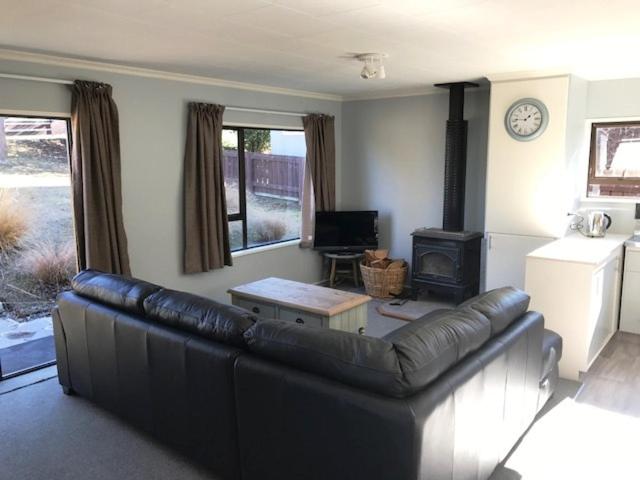 a living room with a leather couch and a fireplace at Naseby Cottage - 24 Leven St in Naseby