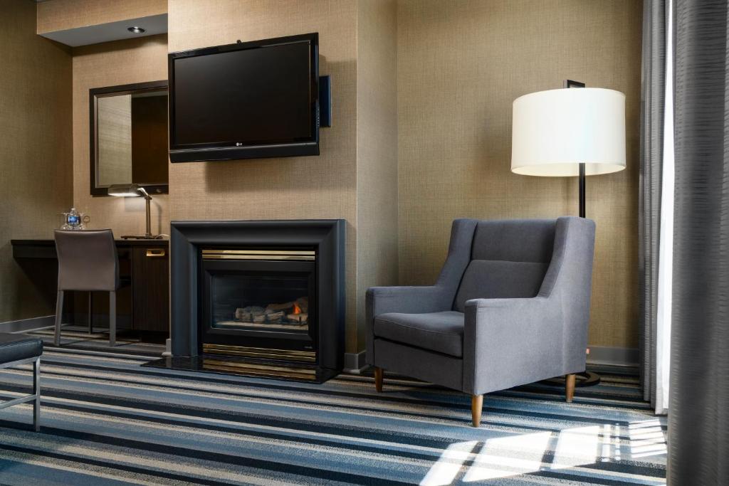 a living room with a fireplace and a chair and a television at Hotel Arts Kensington in Calgary