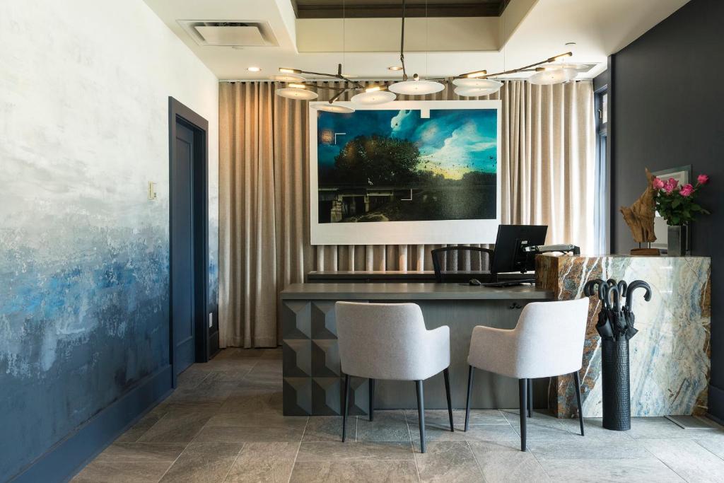 a lobby with a desk with white chairs and a painting at Hotel Arts Kensington in Calgary
