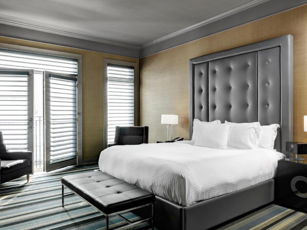 a bedroom with a large bed and a chair at Hotel Arts Kensington in Calgary