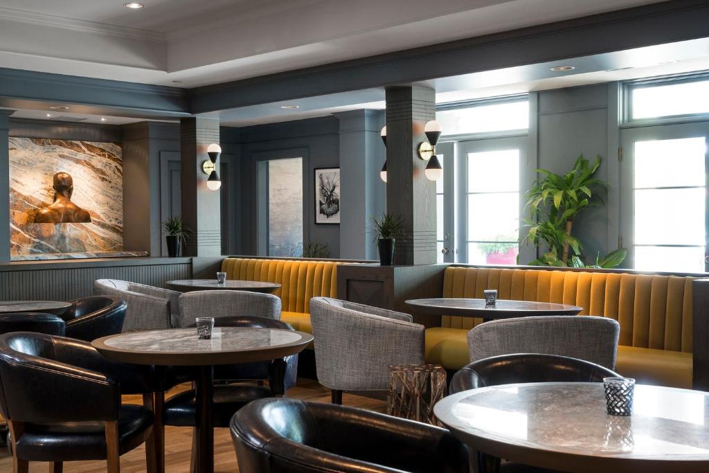 a restaurant with tables and chairs and windows at Hotel Arts Kensington in Calgary