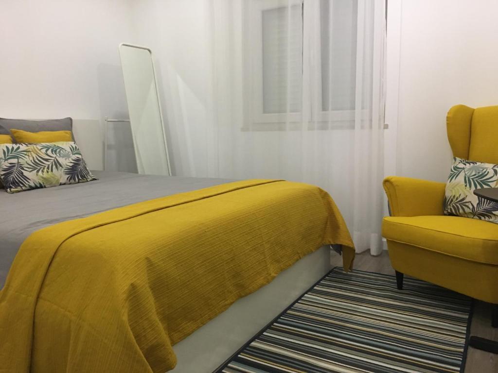 a bedroom with a yellow bed and a yellow chair at Lisboa Comfort Apartment in Lisbon