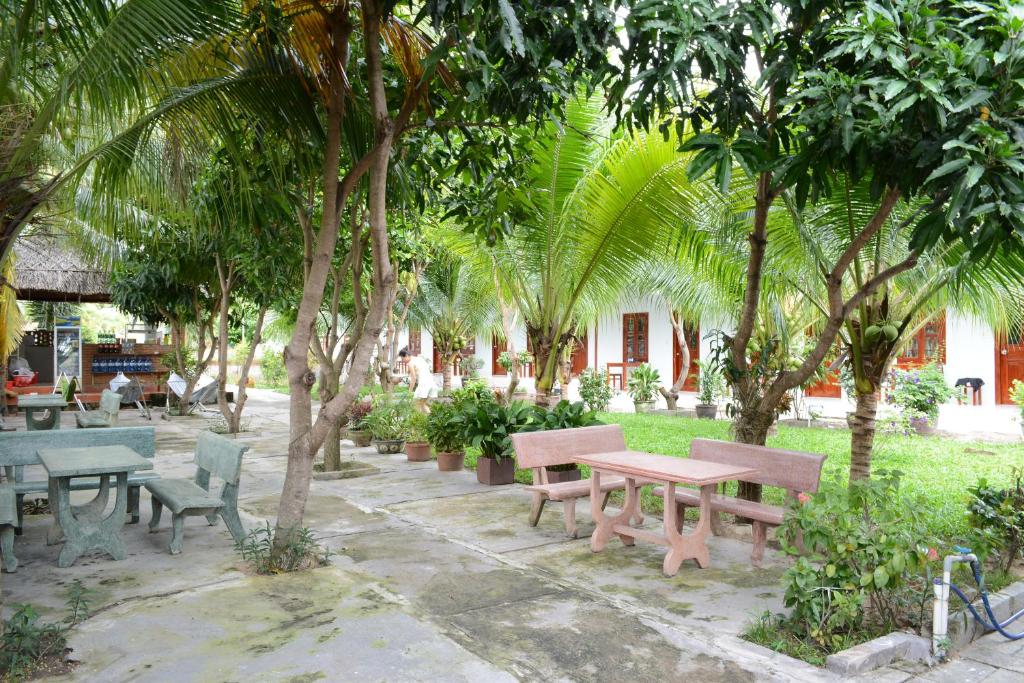 a park with benches and trees and palm trees at Diem Lien Guesthouse in Mui Ne