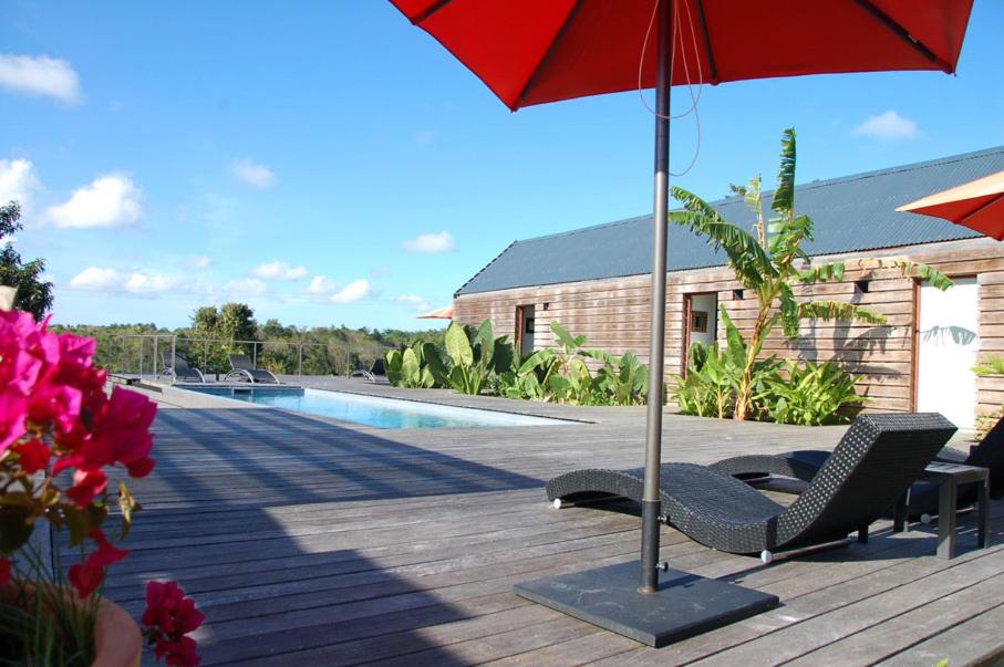 - une terrasse avec 2 chaises et un parasol à côté de la piscine dans l'établissement La Case des Caraïbes, au Gosier
