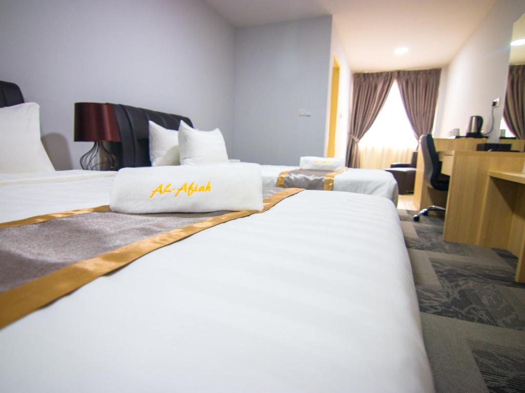 a hotel room with two beds and a desk at Al Afiah Hotel in Bandar Seri Begawan