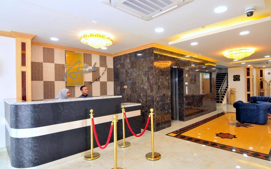 a man standing at a counter in a hotel lobby at Al Afiah Hotel in Bandar Seri Begawan