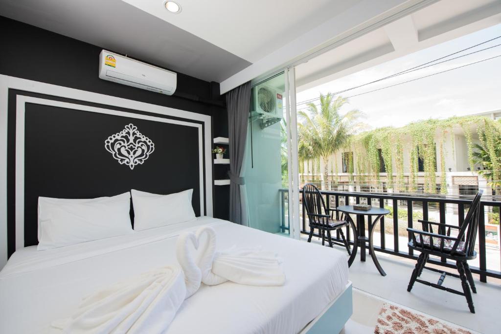 1 dormitorio con cama blanca y balcón en Vacation Time House, en Nai Yang Beach