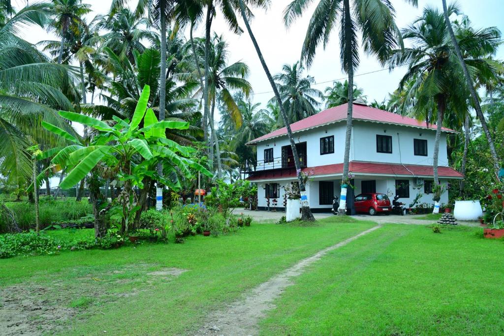 a house with palm trees in front of a yard at Royal Beach Abode in Cochin