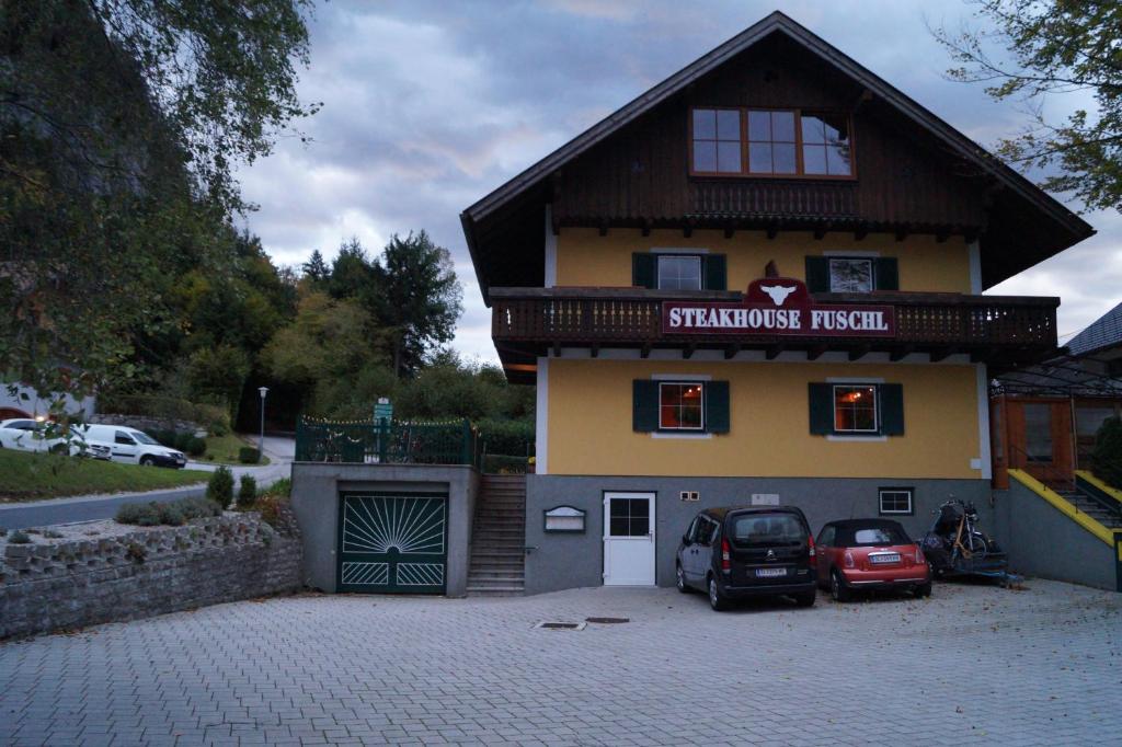 a building with two cars parked in front of it at Steakhouse Fieg in Fuschl am See