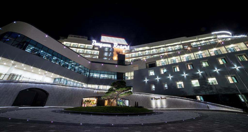 un edificio con un árbol delante de él por la noche en Dongwon Youthhostel en Tongyeong