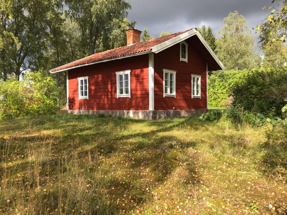 una vieja casa roja en un campo de hierba en Oxelbacka cottage en Enköping