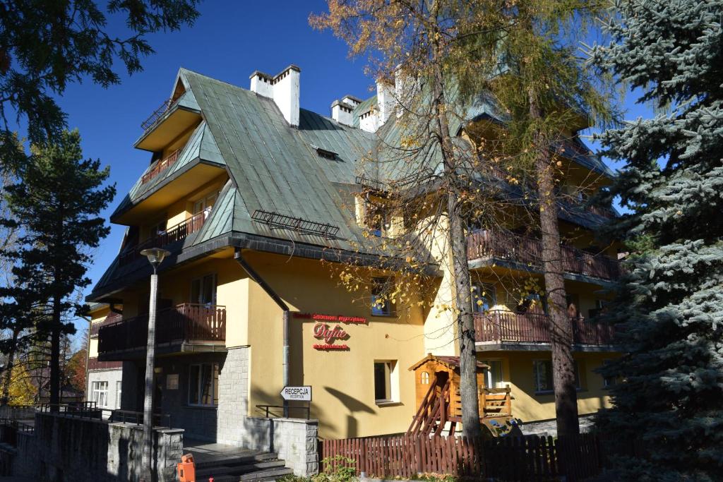 duży żółty dom z zielonym dachem w obiekcie Dafne Zakopane w Zakopanem