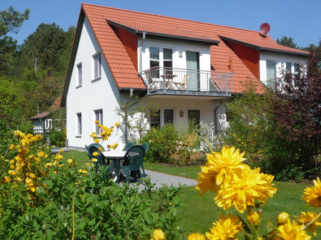 a white house with a table and yellow flowers at Steinbock-Ferienwohnungen in Kolpinsee