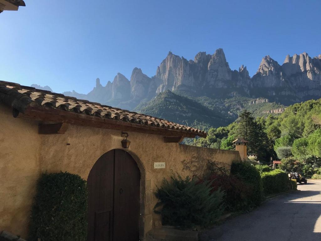 a building with a door and mountains in the background at Montserrat La Calsina in Monistrol