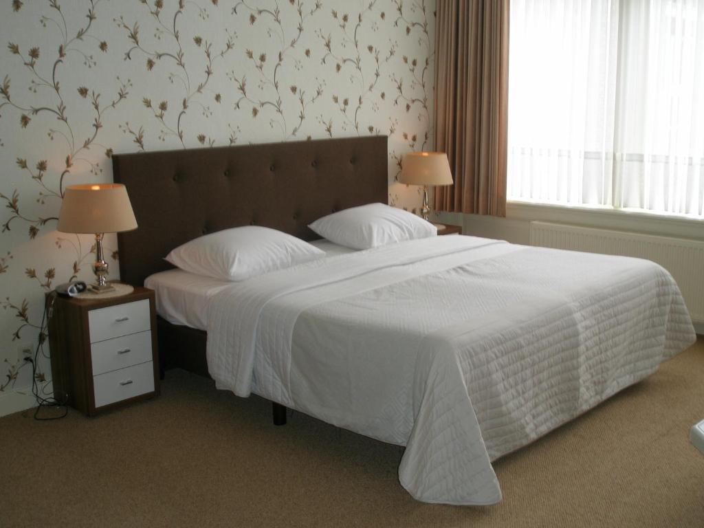 een slaapkamer met een groot bed en een wit dekbed bij Hotel Excelsior in Den Haag
