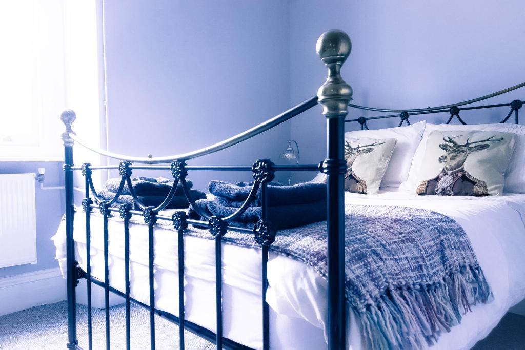 a blue bedroom with a bed with a metal frame at The Old Down Inn in Radstock