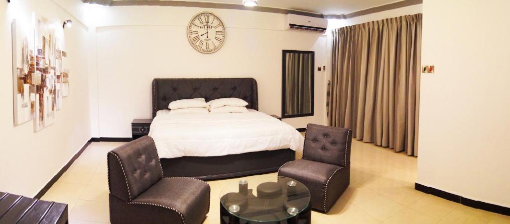 a bedroom with a bed and two chairs and a clock at Econo Lodge in Dar es Salaam