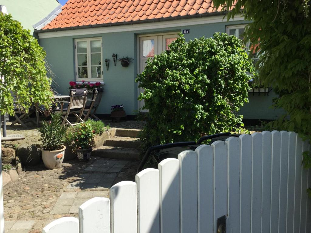 una casa azul con una valla blanca delante de ella en Baghuset en Ebeltoft