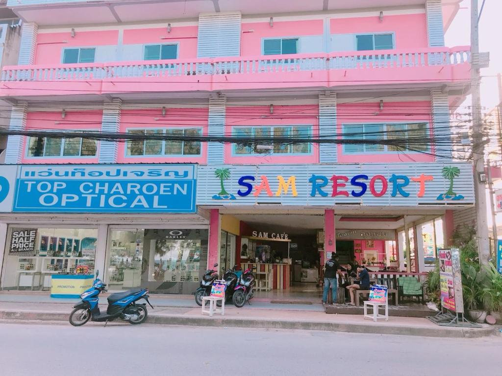 a pink building with motorcycles parked in front of it at Sam Resort Chaam in Cha Am
