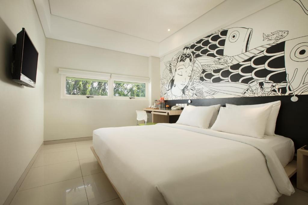 فندق غراندماز بلس المطار  في كوتا: غرفة نوم بسرير ابيض كبير وجدارية
