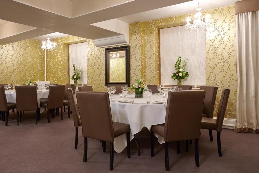 a dining room with a table and chairs and flowers at The Royal Hotel in Ventnor