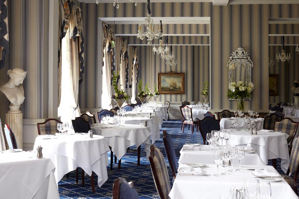 a dining room with white tables and chairs and a chandelier at The Royal Hotel in Ventnor