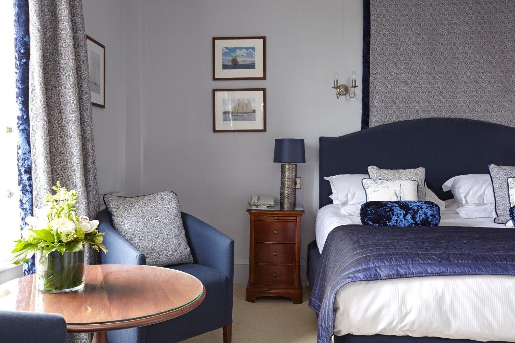 a bedroom with a blue bed and a table and a chair at The Royal Hotel in Ventnor