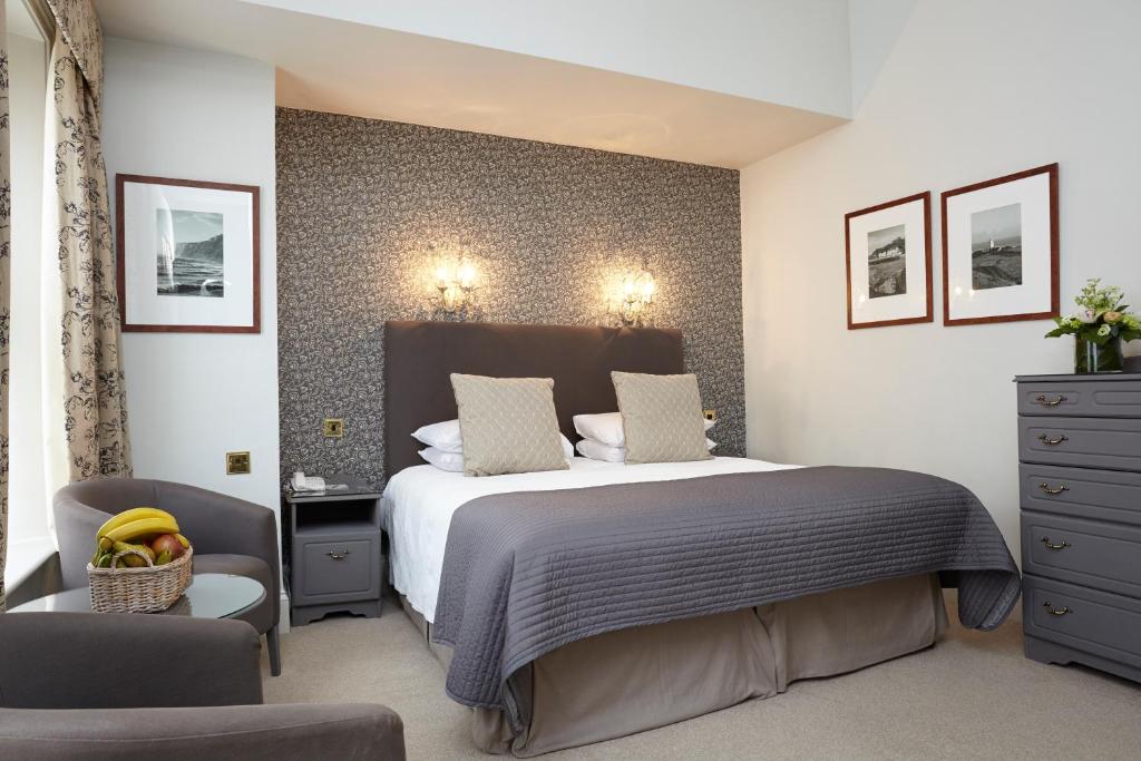 a bedroom with a large bed and two chairs at The Royal Hotel in Ventnor