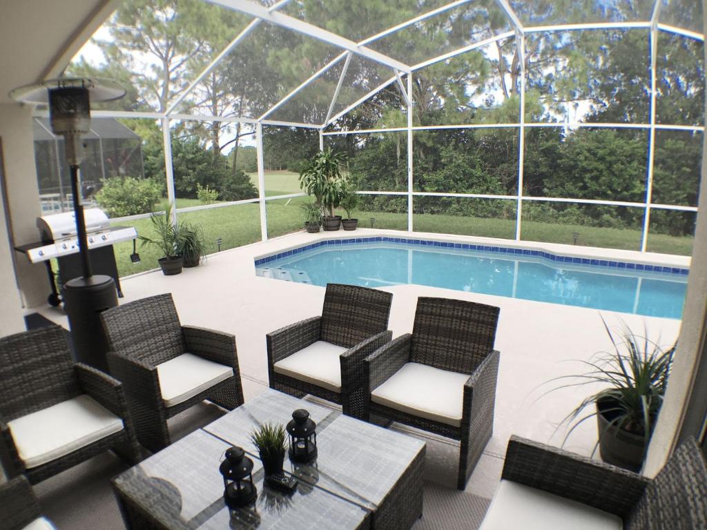 a patio with chairs and a swimming pool with a glass roof at Villa Dunes Court in Haines City