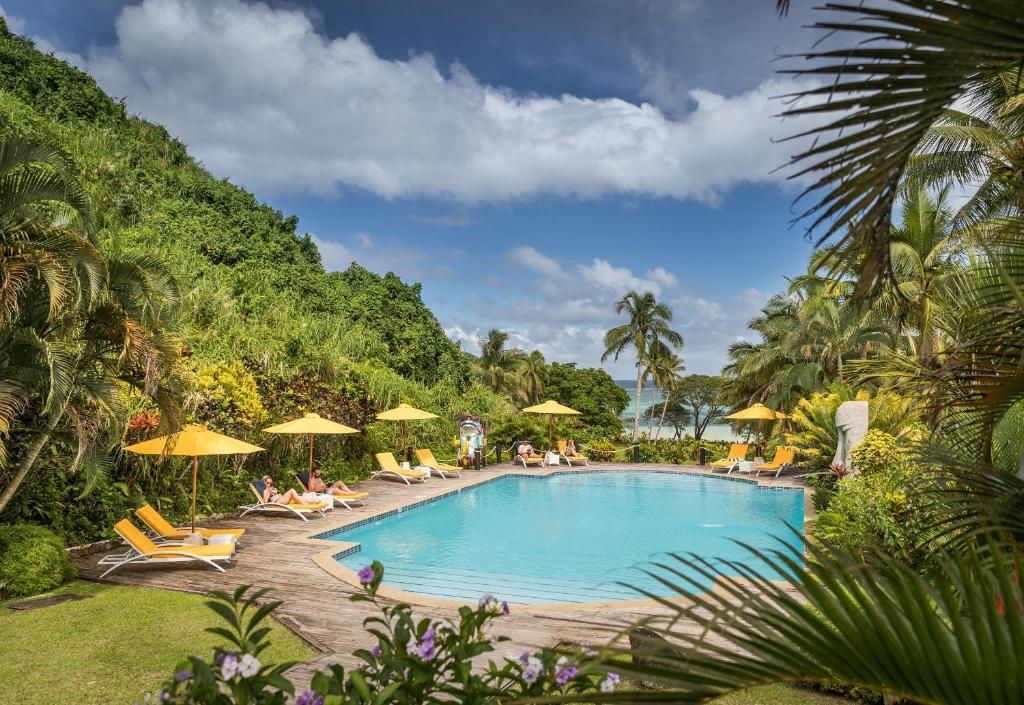 a swimming pool with chairs and umbrellas at Wellesley Resort Fiji in Vunaniu