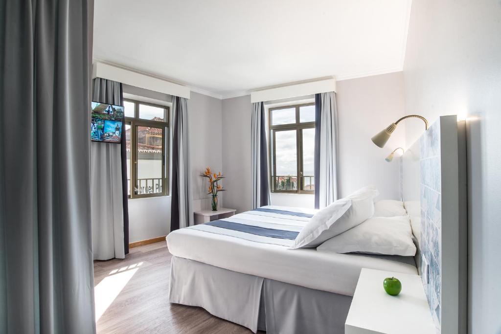 een slaapkamer met een bed en 2 ramen bij Sé Boutique Hotel in Funchal