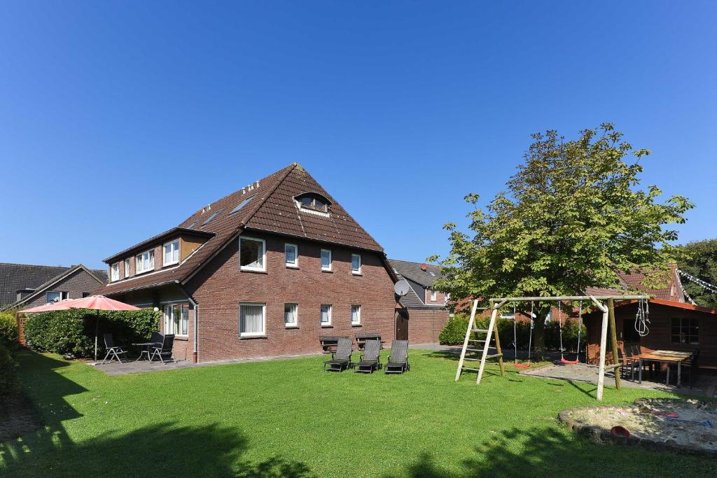 a large house with a yard with a swing at Haus Stoertebeker in Neuharlingersiel