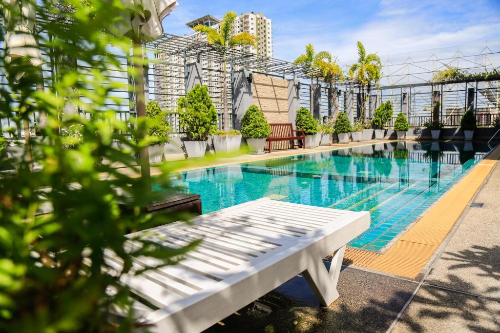 una piscina con un banco blanco junto a un edificio en Northgate Ratchayothin - SHA Extra Plus en Bangkok