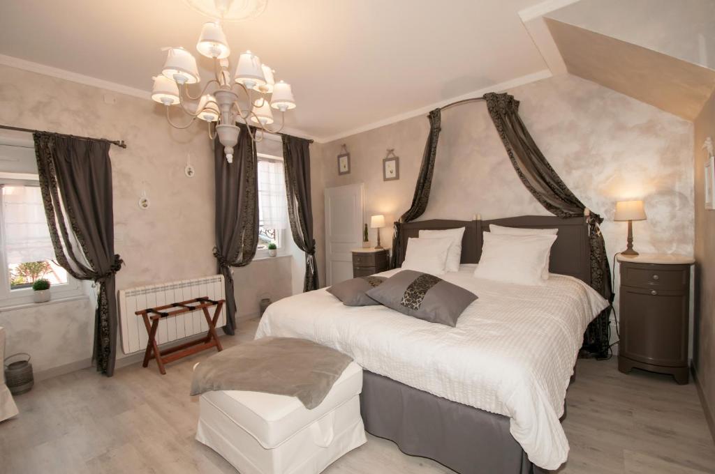 Un dormitorio con una cama grande y una lámpara de araña. en Le Logis Aux Bulles en Verzy