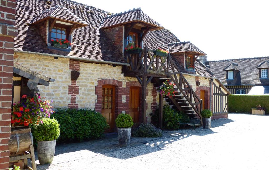 una vieja casa de ladrillo con flores en un patio en Le Pave d'Hotes, en Beuvron-en-Auge